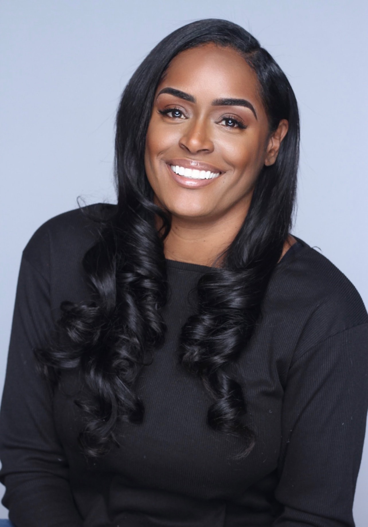 Aubree Bravo — black ribbed top, curls, big smile